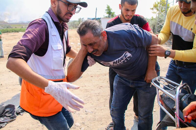 GAZA CITY, GAZA - OCTOBER 7: A paramedic helps an injured man near the border fence between the Gaza Strip and Israel on October 7, 2023 in Gaza City, Gaza. The Palestinian militant group Hamas launched a missile attack on Israel today, with fighters simultaneously crossing the border from Gaza. Israel has declared a state of war. (Photo By Ahmad Hasaballah/Getty Images)