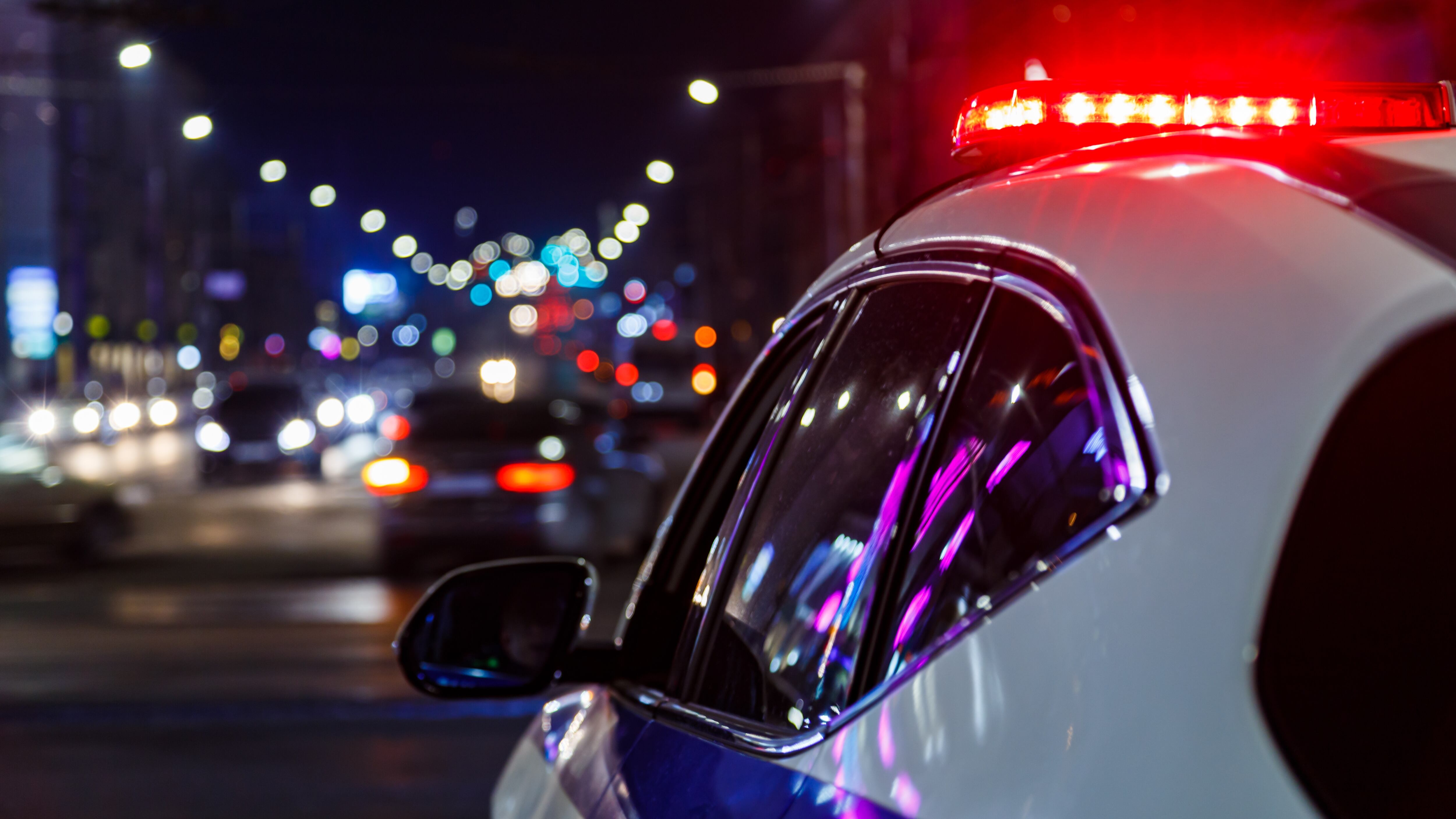 police car lights at night in city with selective focus and blurry car traffic